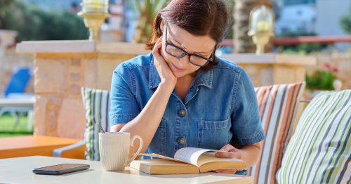 Mujer en menopausia leyendo en una mesa para combatir la pérdida de memoria